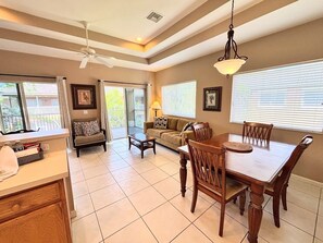 A spacious living area with a dining table, sofa, and a ceiling fan.