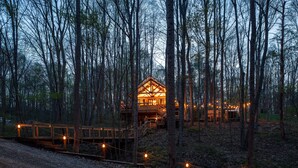 Eine Holzhütte im Wald, verbunden durch einen Feldweg.