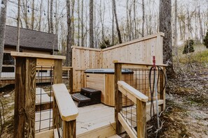 A wooden sauna structure with benches and a hot tub, surrounded by trees.