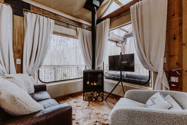 A cozy cabin interior with a fireplace, leather sofas, and a television.