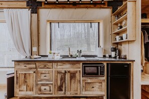 Une cuisine compacte avec des meubles en bois, un four à micro-ondes encastré et un réfrigérateur.