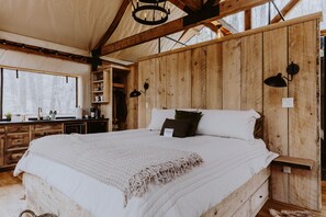 Un dormitorio de madera con una cama grande, un armario de madera y una ventana con vistas a un bosque.