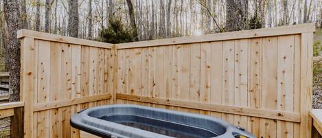 A hot tub in a wooden deck area surrounded by trees.
