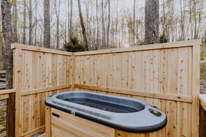 A hot tub in a wooden deck area surrounded by trees.