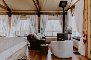 Un interior acogedor de cabaña con chimenea, muebles de madera y ventanas amplias.