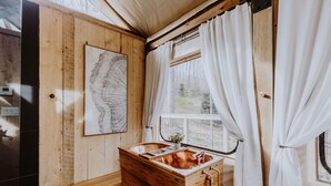 Ein Holzblockbau-Innenraum mit einer Holzwanne, einem Fenster mit Vorhängen und einer Karte an der Wand.