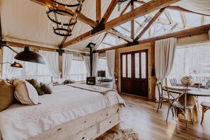 A cozy room with a large bed, a fireplace, a dining table with chairs, and a globe on the table.
