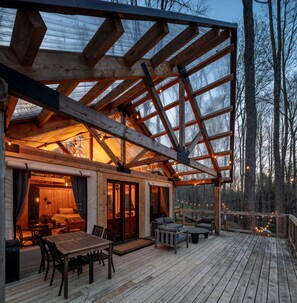 A wooden deck with a dining area, a sofa, and a table. - The Reserve | Hocking Hills (South Bloomingville)