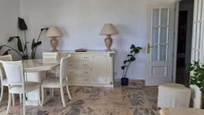 Un comedor con una mesa y sillas, un armario con cajones, dos lámparas y una puerta con panel de vidrio.