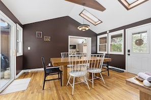 A dining area with a wooden table and chairs, a ceiling fan, and a skylight.