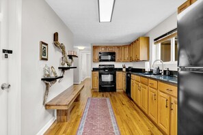 Una cocina con armarios de madera, microondas integrado, horno y refrigerador.
