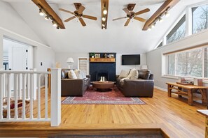 A spacious living room with a fireplace, two sofas, a coffee table, and a TV.
