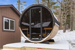 Una estructura esférica con puerta de cristal, terraza de madera y un pequeño edificio con ventana.