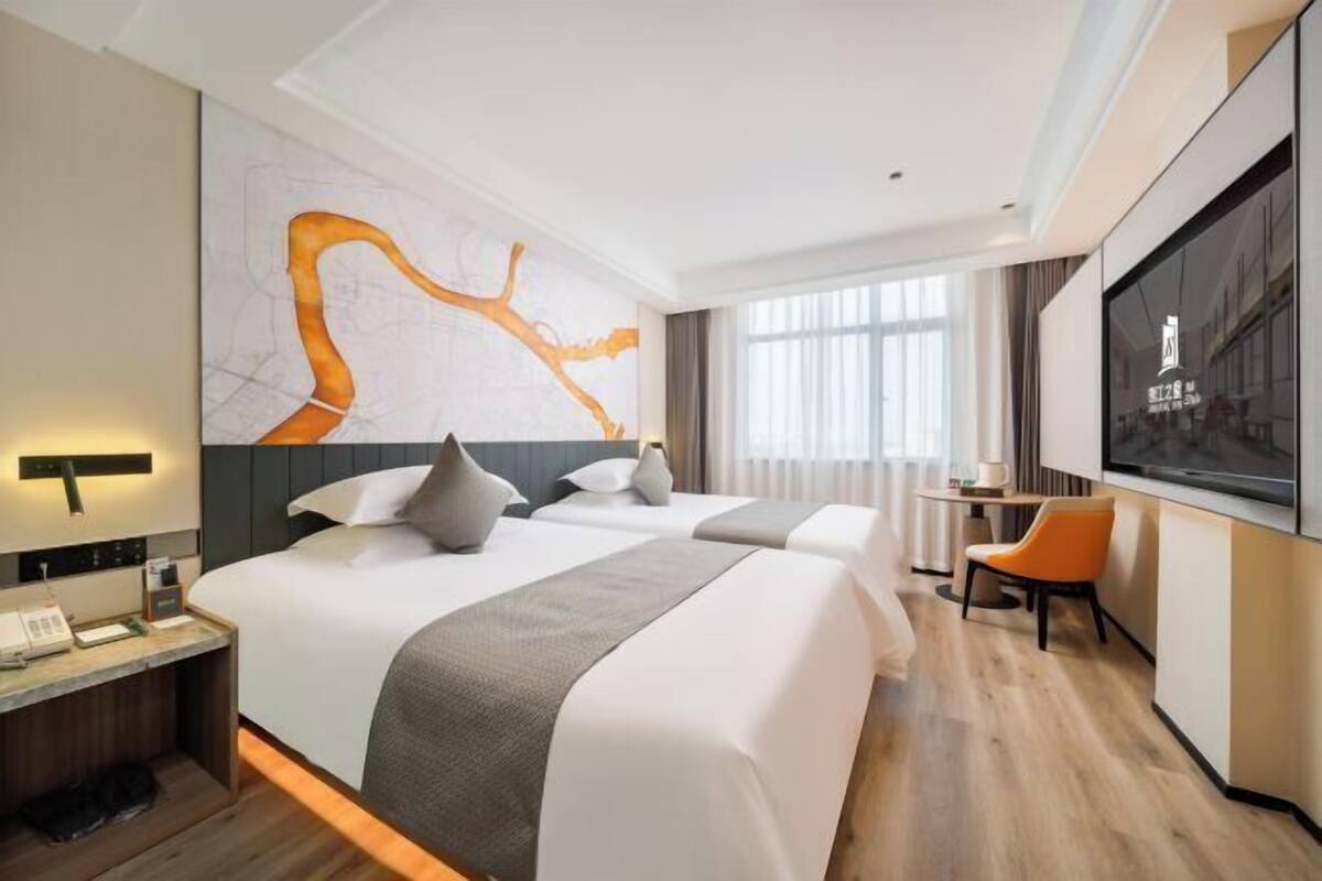 A hotel room with a large bed, a desk with a phone, a chair, and a TV on the wall.