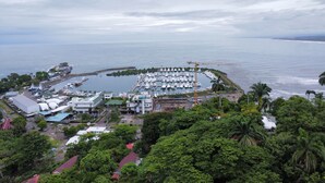 A marina with numerous boats docked, surrounded by lush greenery and buildings with red roofs. - Ocean Breeze by Casa Pargo (Provincia de Puntarenas)