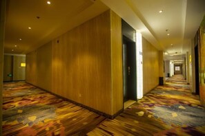 Un pasillo de hotel con piso alfombrado, paredes de madera y un ascensor.
