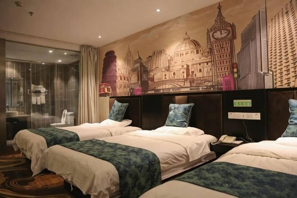A hotel room with two beds, a large window, and a cityscape mural on the wall.