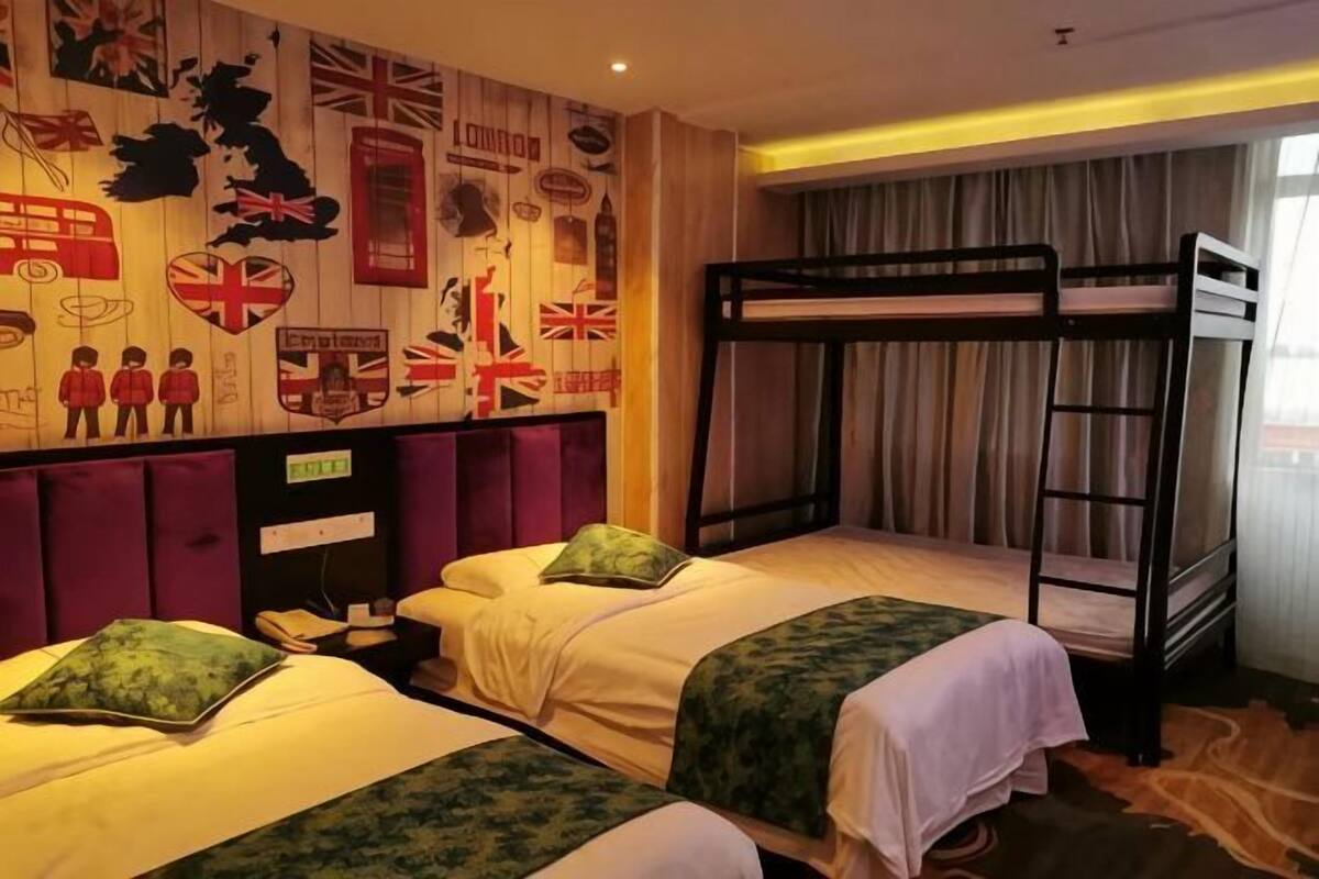 A hotel room with two beds, a bunk bed, a map-themed wall, and a window with curtains.