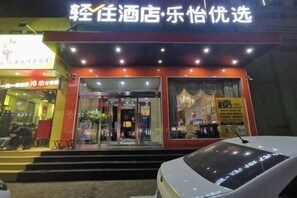 A hotel entrance with a red facade, glass doors, and a sign above the entrance.