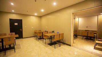 A conference room with tables and chairs, a door, and a projection screen.