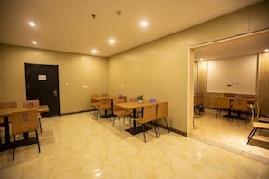 A conference room with tables and chairs, a door, and a projection screen.