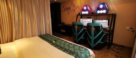 Una habitación de hotel con una cama, un escritorio con dos monitores y un cartel en la pared que dice 'LOVE'.