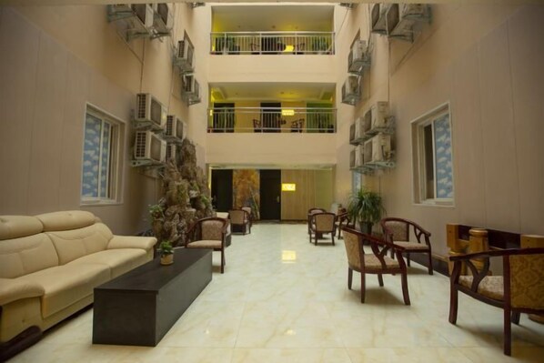A spacious lobby with a high ceiling, multiple seating areas, and a central decorative piece.
