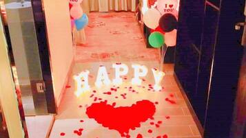 A hallway with a heart-shaped decoration on the floor, balloons, and a 'HAPPY' sign.