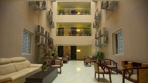 Un'ampia hall con un divano color beige, diverse poltrone, un tavolino da caffè e la reception.