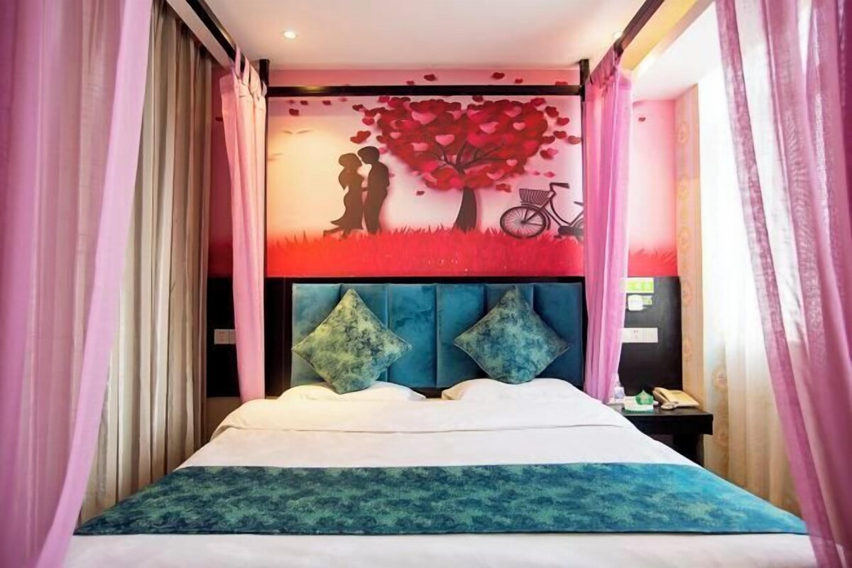 A bed with a headboard, a wall with a mural, and curtains.