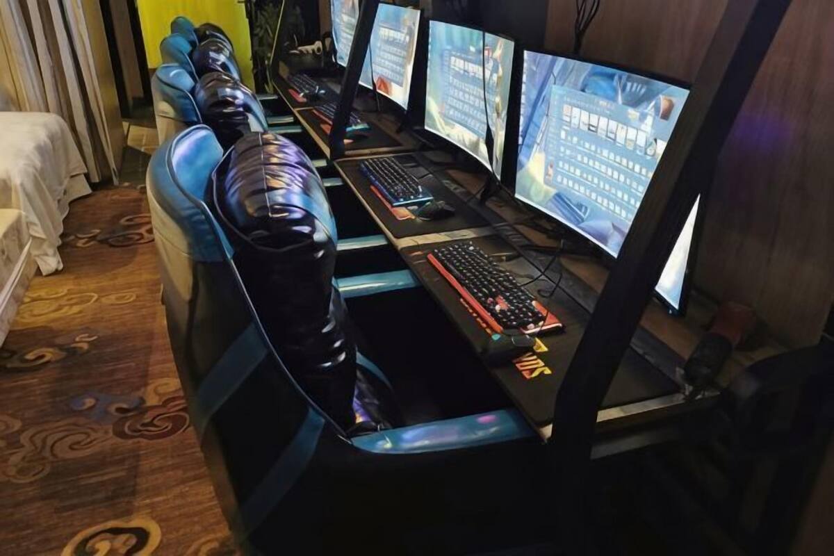 A row of gaming stations with multiple monitors, keyboards, and mice.