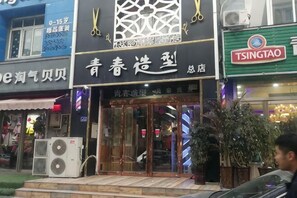 A storefront with a large sign, air conditioning units, and a potted plant outside. - Tehaote Hotel of Zheng Zhou (Zhengzhou)