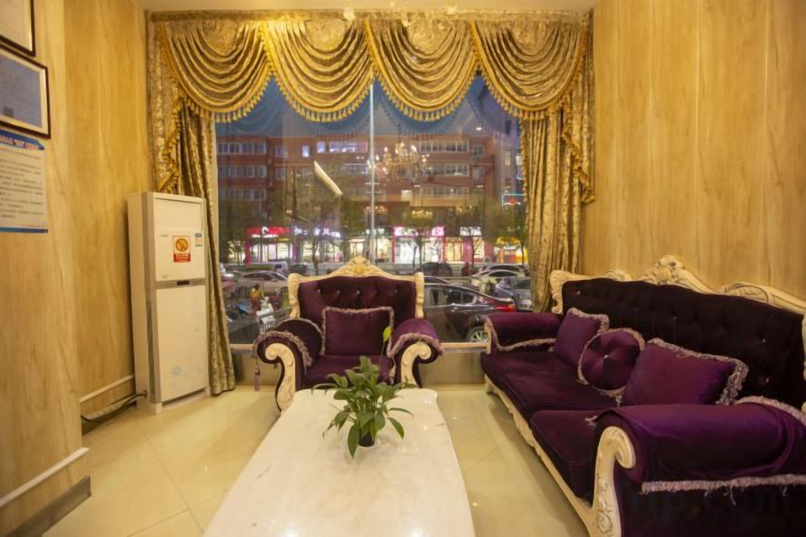 A room with a sofa, armchairs, a coffee table, and a view of a busy street through large windows.