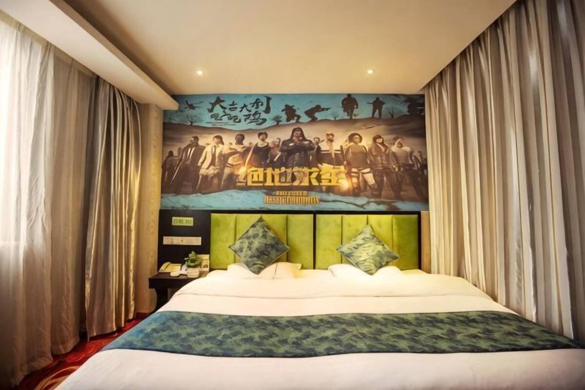 A hotel room with a large bed, a headboard with decorative elements, a wall with a poster, and curtains on the windows.