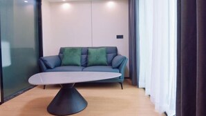 A modern living room with a sofa, a coffee table, and a glass partition. - Jin Jiang Hotel (Cangnan)