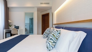 Ein Hotelzimmer mit einem großen Bett, einem Schreibtisch mit einem Laptop und einer Dusche.
