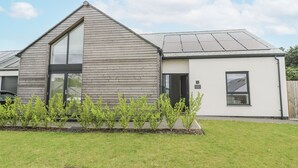 Et moderne hus i to etager med et skråt tag, et stort vindue i første sal og en dør ind til huset.