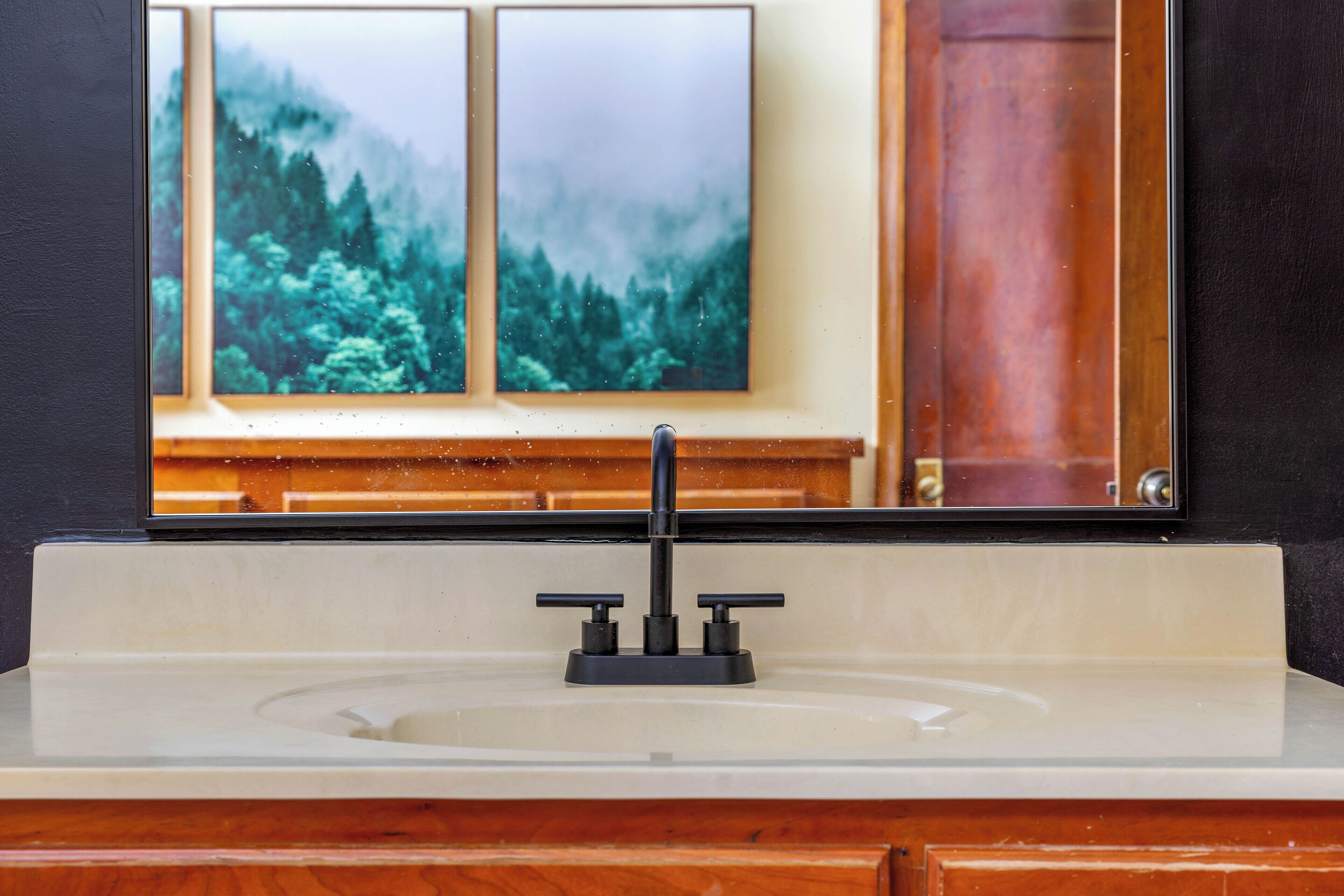 A bathroom with a white sink, a black faucet, and a mirror above it.