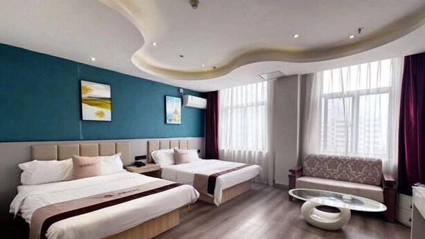 A hotel room with two beds, a sofa, a glass coffee table, and artwork on the walls. - Ward Aladdin Hotel (Changjiang East Road Huangdao Golden Beach Branch) (Qingdao)