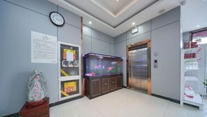 A lobby with a clock, a fish tank, a stone sculpture, and an elevator. - Ward Aladdin Hotel (Changjiang East Road Huangdao Golden Beach Branch) (Qingdao)