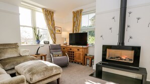 A cozy living room with a fireplace, comfortable seating, and a television. - The Bolt Hole (Kendal)
