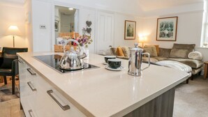 A modern kitchen with a central island, a dining area with a sofa, and a living room with a couch. - The Bolt Hole (Kendal)