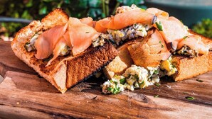 A sandwich on a wooden board with a yellow flower in the background. - Il Bekka Suites (Rabat)