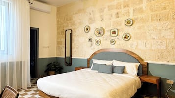 Un dormitorio con piso a cuadros, estructura de cama de madera, un espejo grande y una pared con platos decorativos.