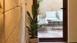A hallway with a potted plant, a door leading to an outdoor seating area, and a staircase. - Il Bekka Suites (Rabat)