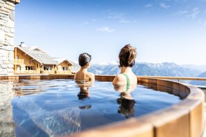Two people in a hot tub with a mountain view.
