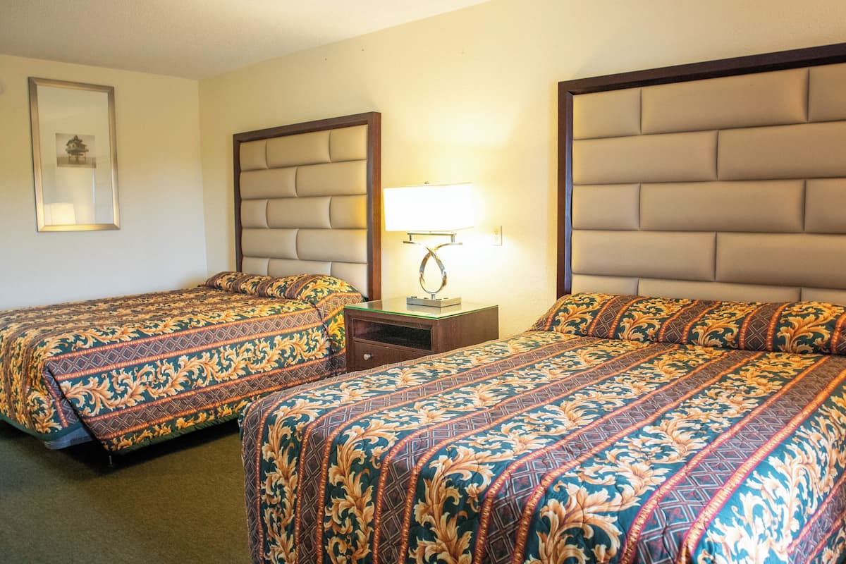 Une chambre d’hôtel avec deux lits, chacun doté d’une tête de lit et d’une table de chevet avec une lampe.