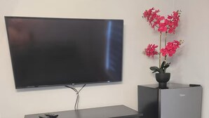A modern living room with a flat-screen TV mounted on the wall, a black dresser with drawers, and a silver refrigerator. - Private 1-Bedroom Retreat with Poolside Vibes (Los Angeles)
