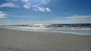 A beach with a clear sky and sunlight reflecting on the water. - Posh, New, Ocean View Townhome in gorgeous Emerald Isle Perfect for families (Emerald Isle)