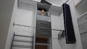Une pièce compacte dotée d’une armoire intégrée, d’un étendoir et d’un petit coin repassage.